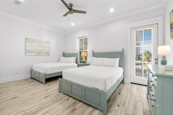 Un dormitorio con dos camas, ventilador de techo, ventana con persianas y vistas al exterior.