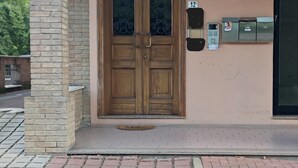 A building entrance with a wooden double door, a brick archway, a hanging light fixture, and a wall-mounted mailbox. - Alby's apartment, in the Motor Valley with private parking (Formigine)