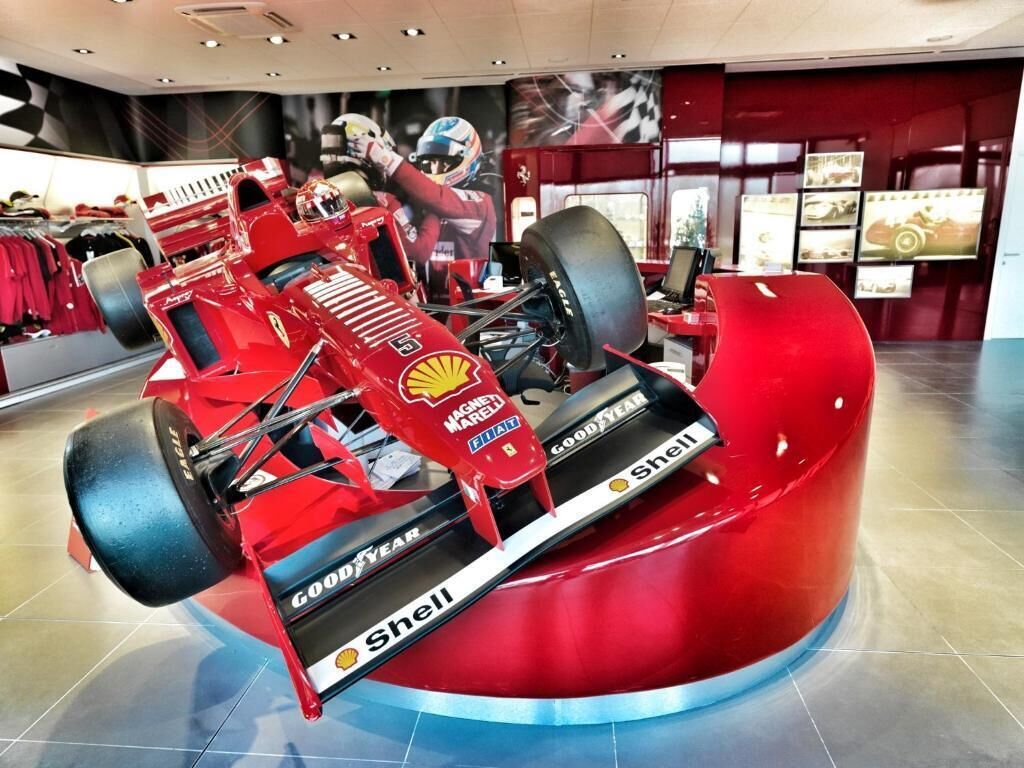 A red Formula 1 car with sponsor logos in a showroom.