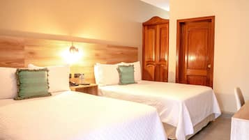 Een hotelkamer met twee bedden, een houten hoofdbord, een nachtkastje met een telefoon en een houten deur.