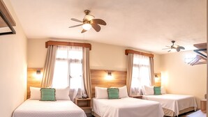 Habitación de hotel con dos camas, ventilador de techo y ventana con cortinas.