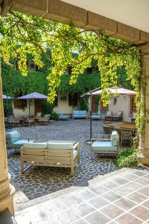 An outdoor patio with stone flooring, wicker furniture, and umbrellas providing shade. - Hotel Casa Carmina by AHS (Antigua Guatemala)