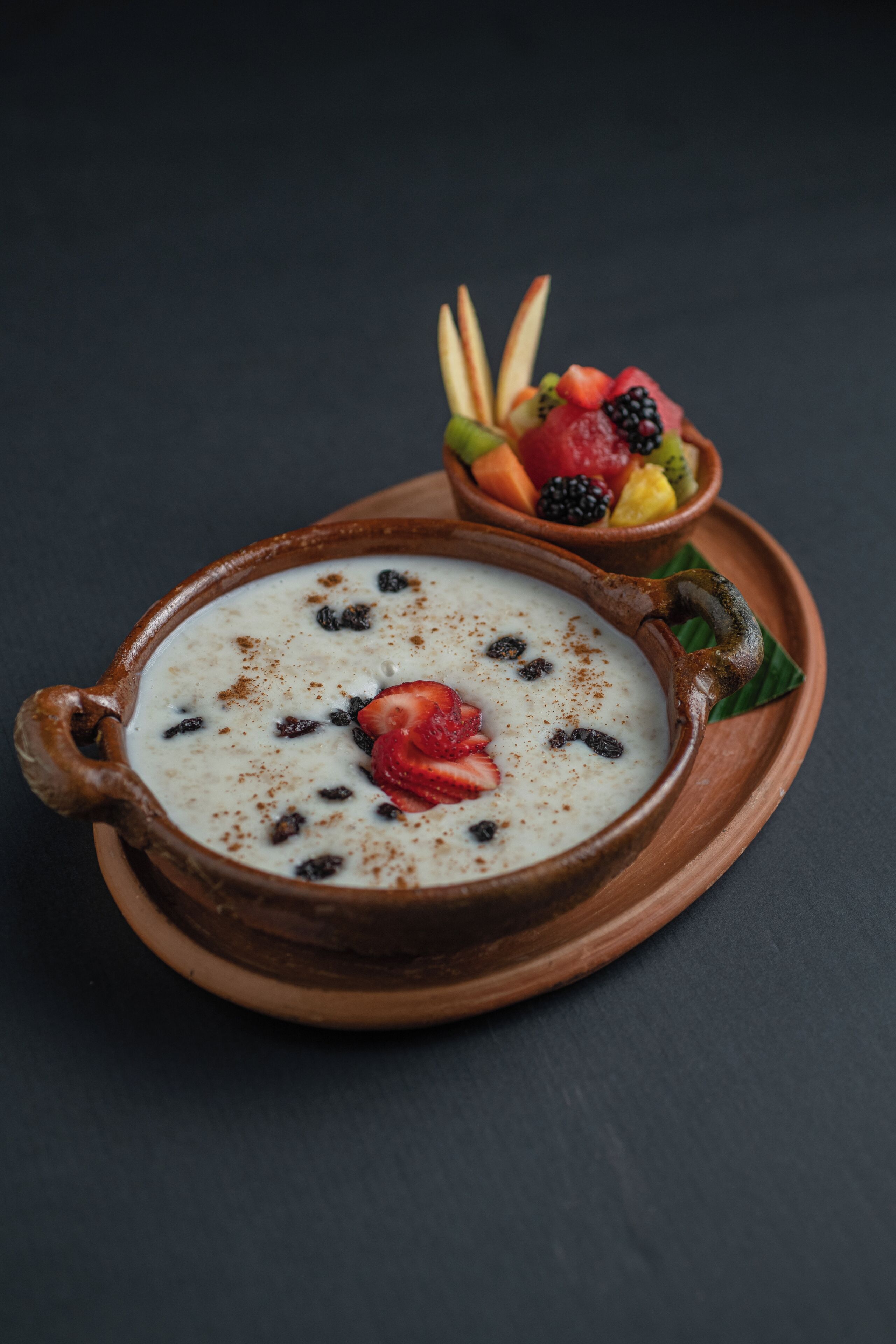 Un postre en un tazón de cerámica con frutas y una fresa encima.