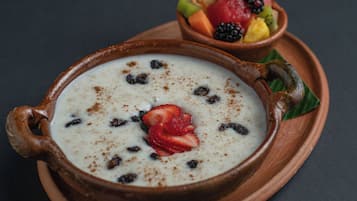 Un postre en un tazón de cerámica con frutas y una fresa encima.