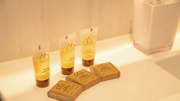 Four bottles of shampoo and two bars of soap on a white countertop.
