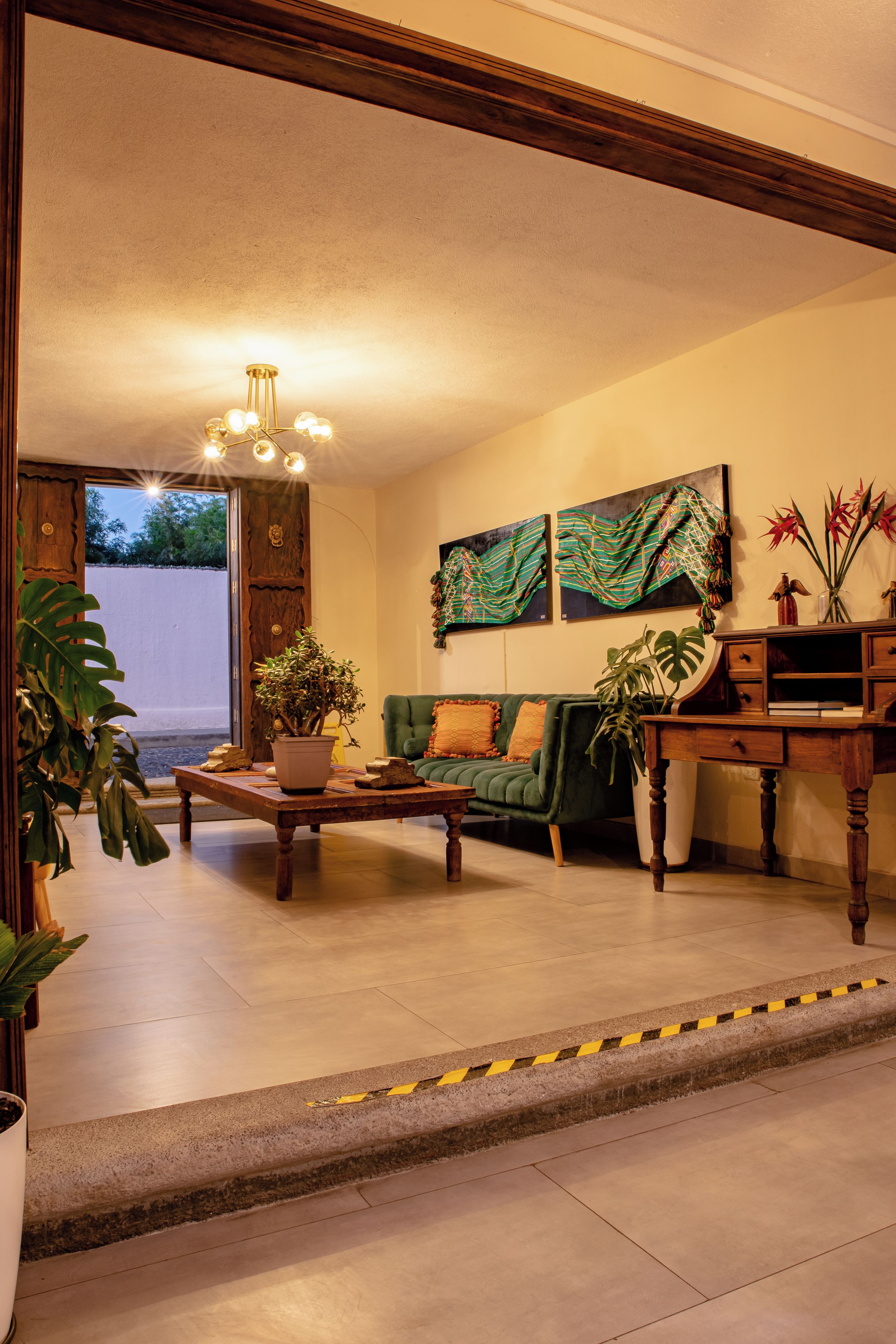 A living room with a green sofa, a wooden coffee table, and a potted plant.