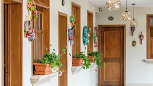 Un pasillo con puertas de madera, plantas en macetas y adornos colgantes.