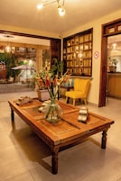 Una mesa de comedor de madera con un jarrón de flores en vidrio, una silla amarilla y un banco de madera.