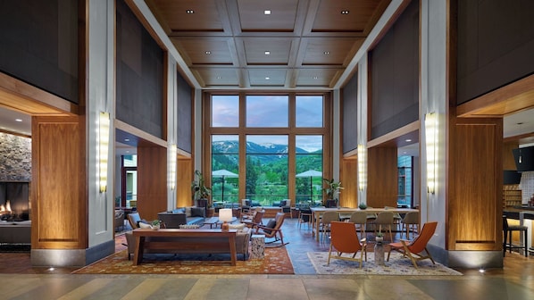 Un hall d’entrée spacieux avec un grand espace salon, une cheminée et une vue sur les montagnes grâce à de grandes fenêtres.