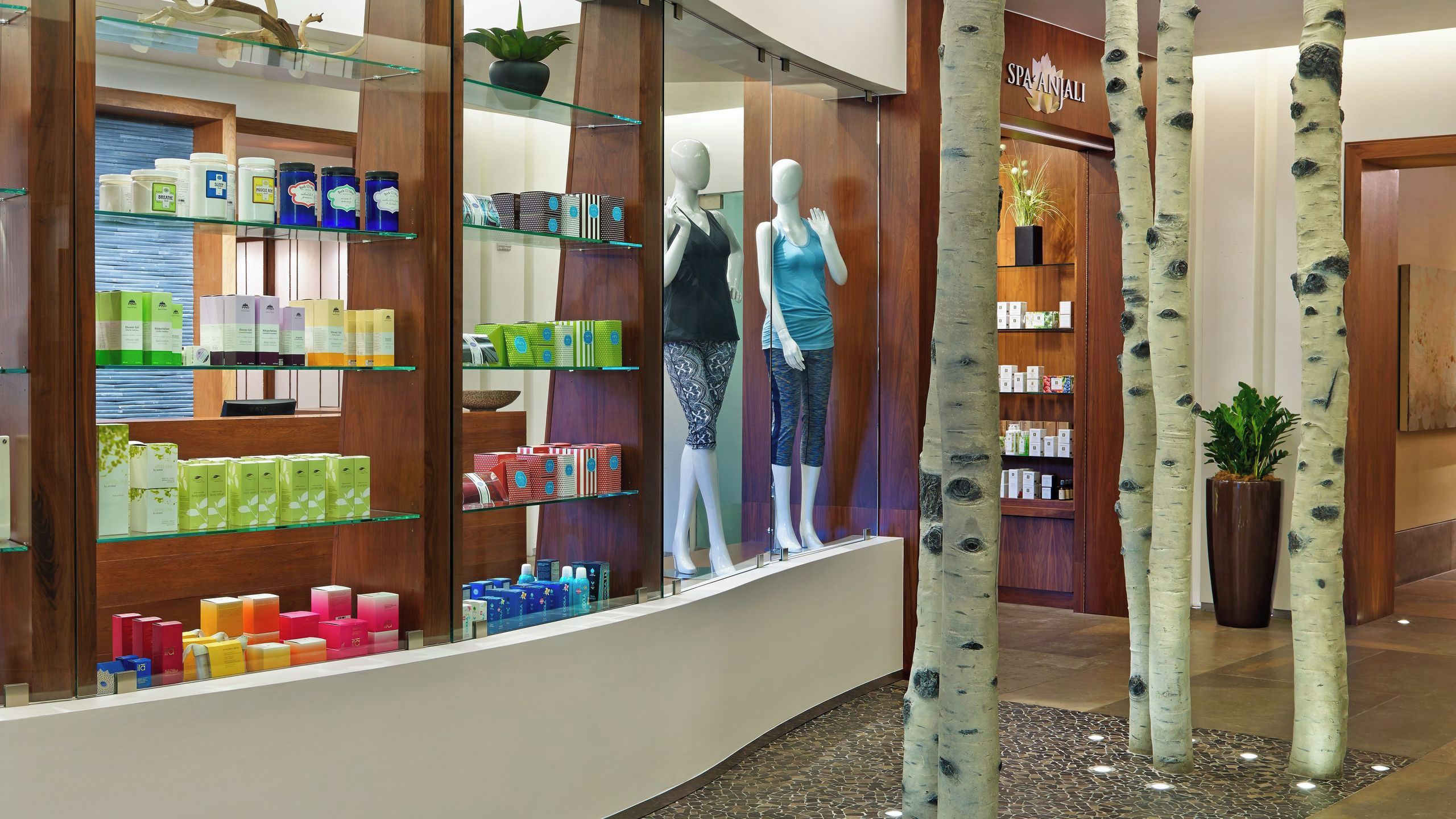 A spa store with shelves of products, two mannequins, and birch tree decorations.