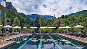A swimming pool with lounge chairs and umbrellas, surrounded by mountains and trees. - Beaver Creek Solace by Avantstay Studio w/ Resort Pool + Hot Tub Premier Avon Location (Avon)