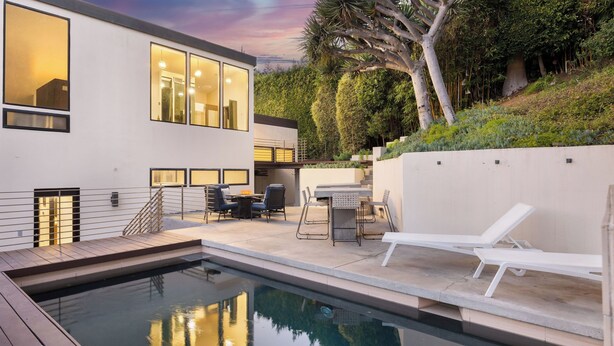 A modern outdoor pool area with a dining setup and lounge chairs.