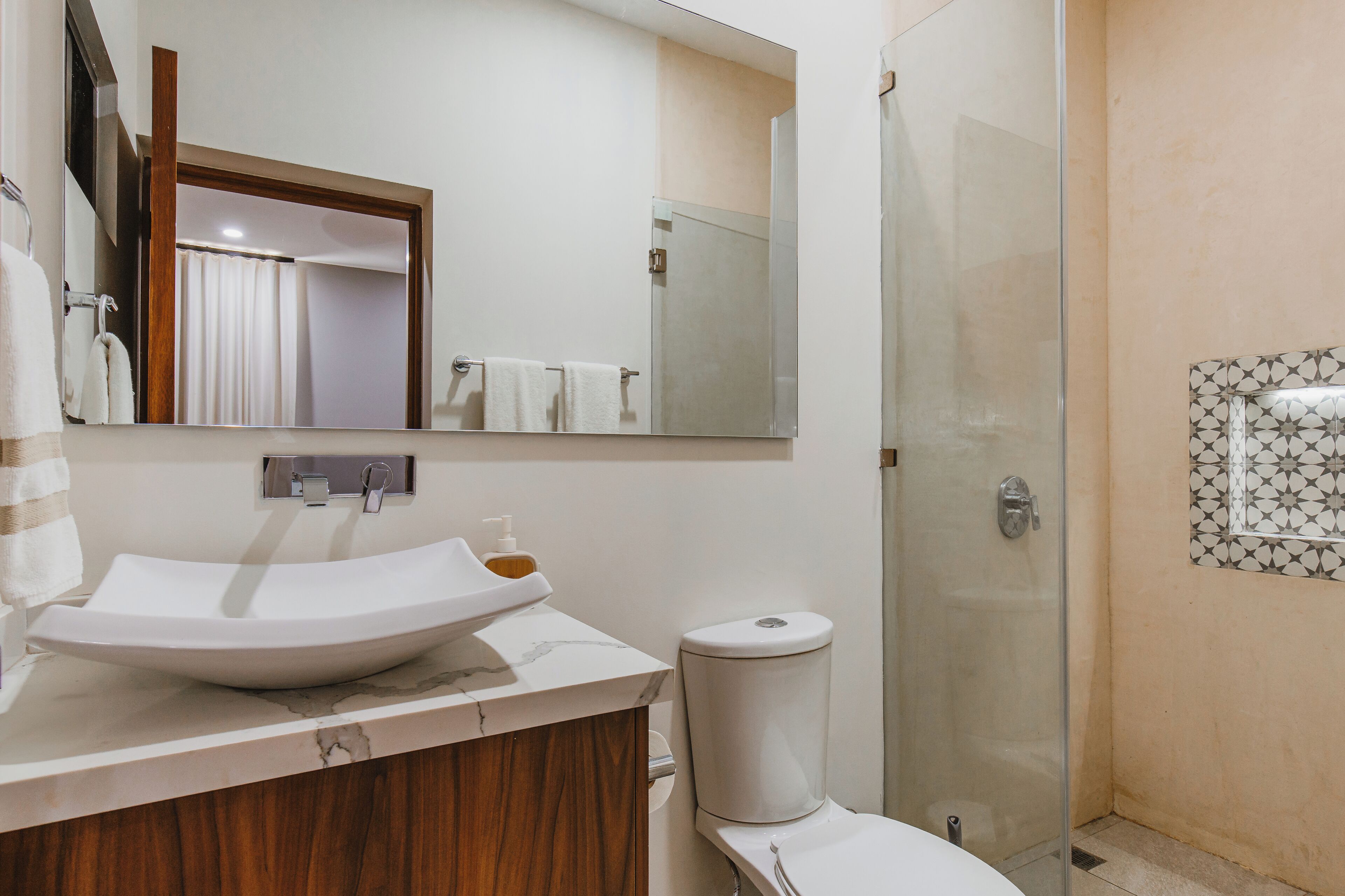 A bathroom with a white sink, a mirror, a toilet, and a shower.