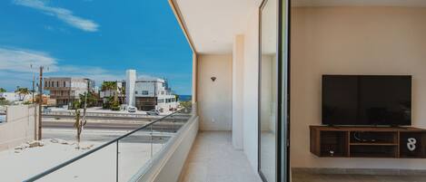 A balcony with a clear view of the street and buildings, a flat-screen TV, and a wooden entertainment unit.
