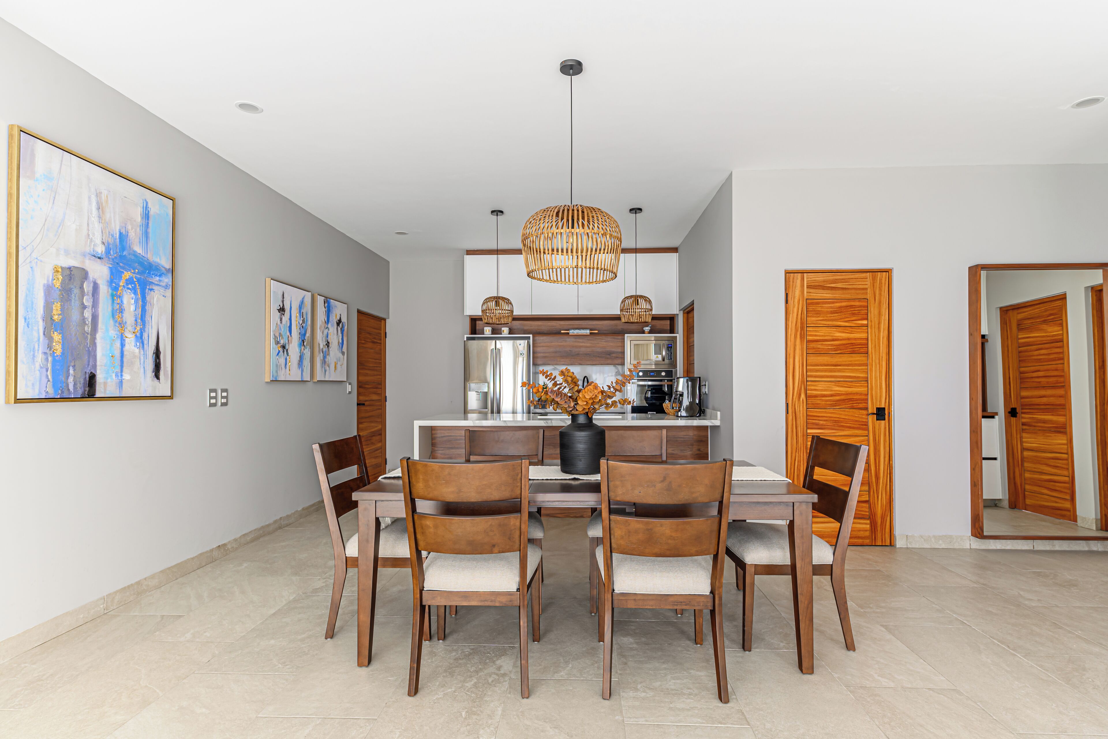 Un comedor moderno con una isla central, sillas de madera y un cuadro grande en la pared.