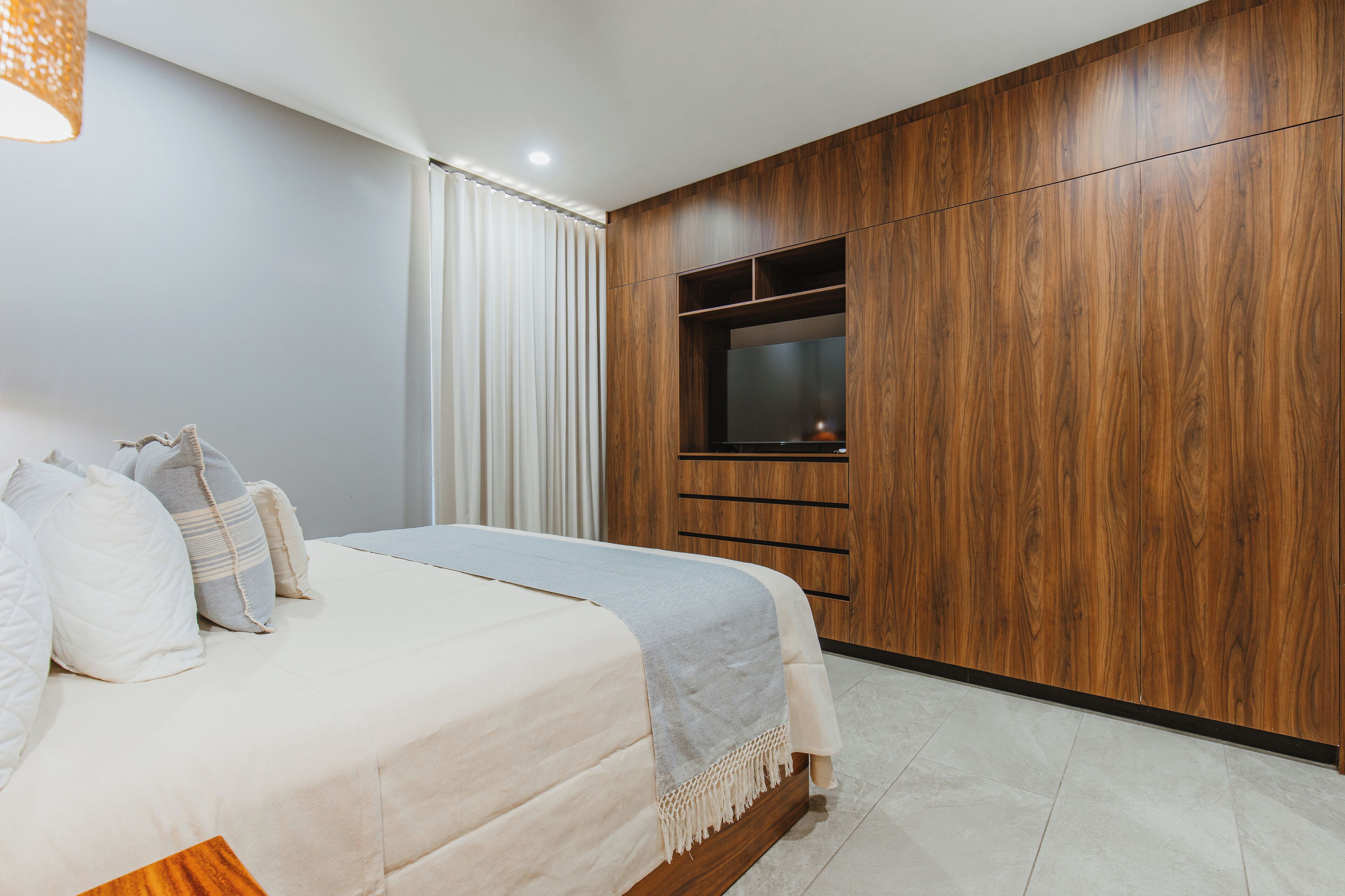 Een slaapkamer met een bed, een televisie en een houten garderobe.