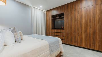 Een slaapkamer met een bed, een televisie en een houten garderobe.