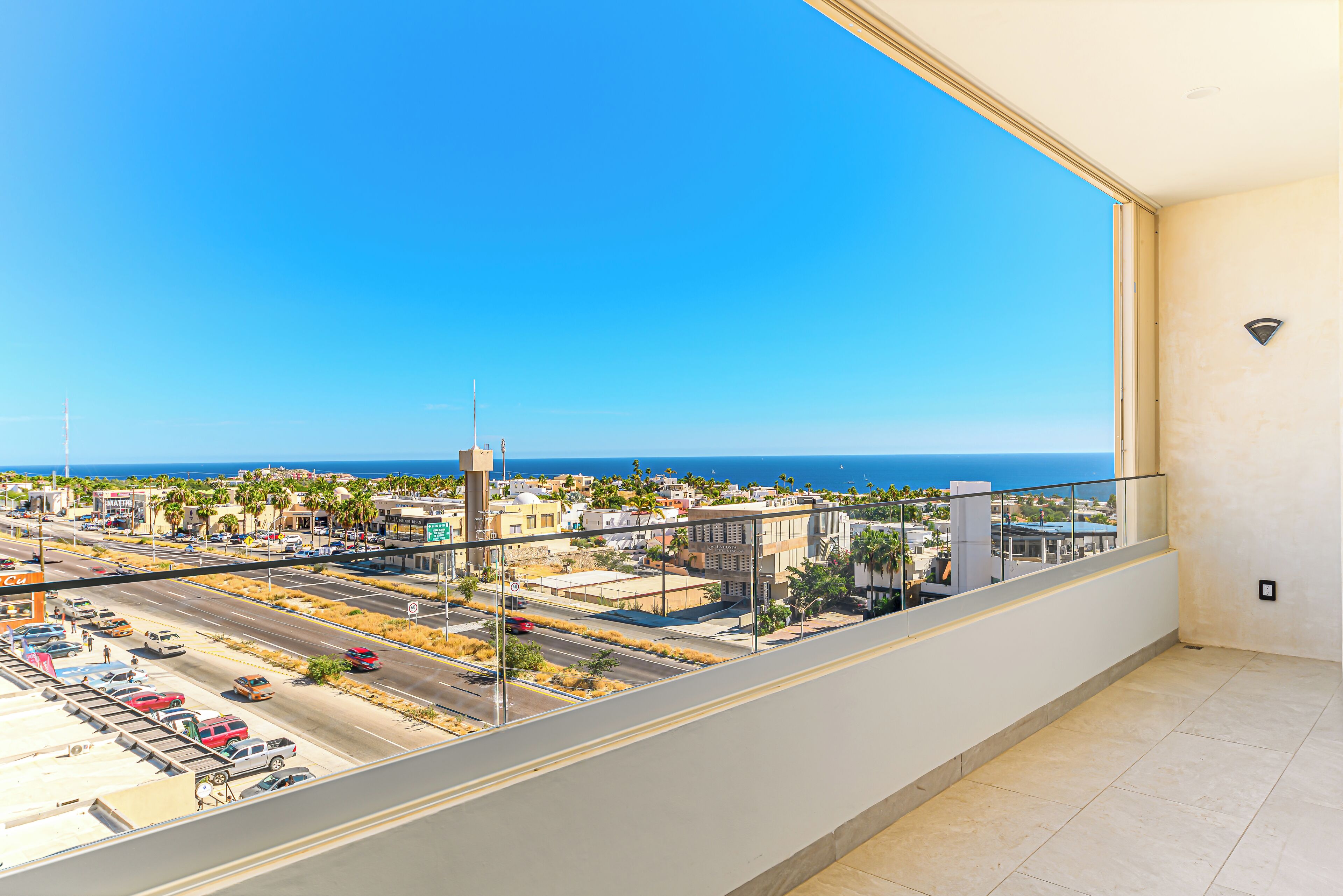 Un balcón con vistas a un paisaje urbano costero, que incluye edificios, calles y el mar.