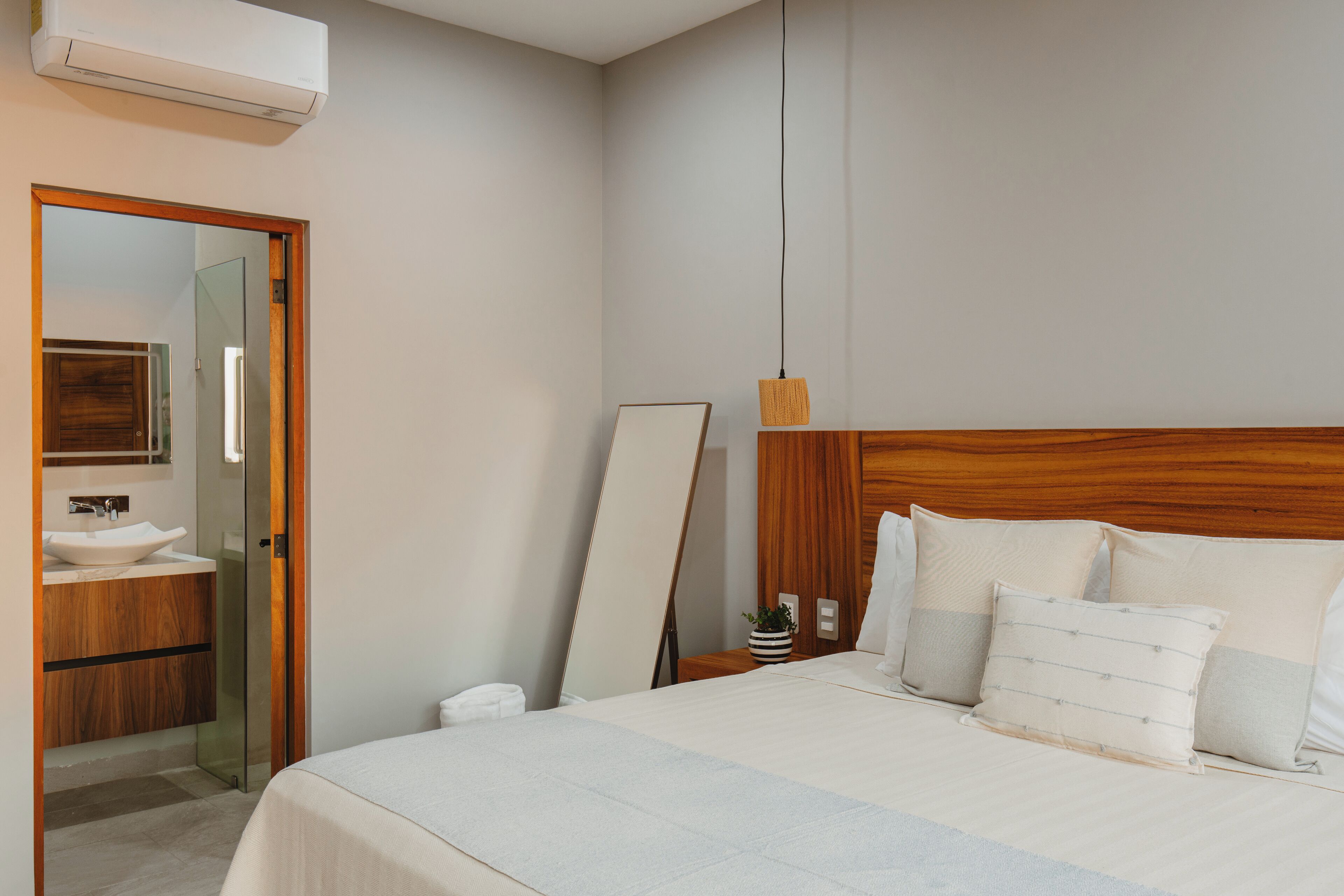 Une chambre à coucher moderne avec un grand lit, une table de chevet et un miroir.