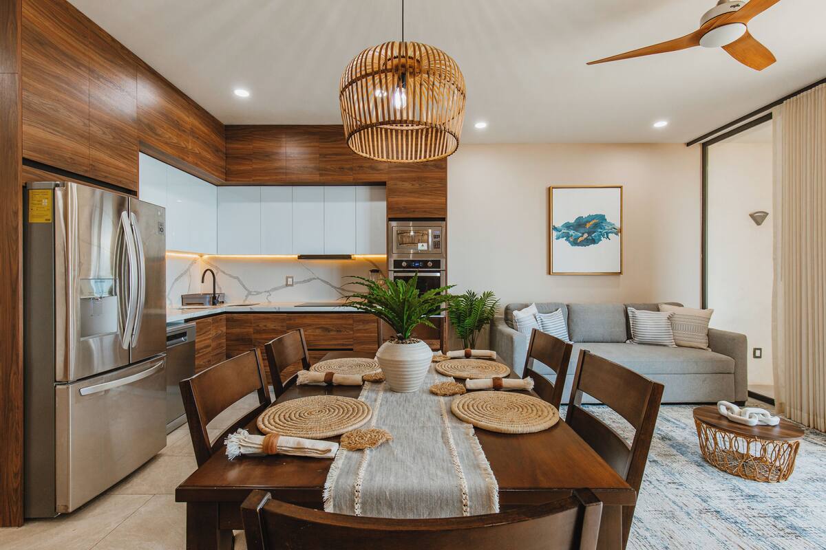 A modern kitchen with a built-in oven, a refrigerator, and a dining area with a wooden table and chairs.