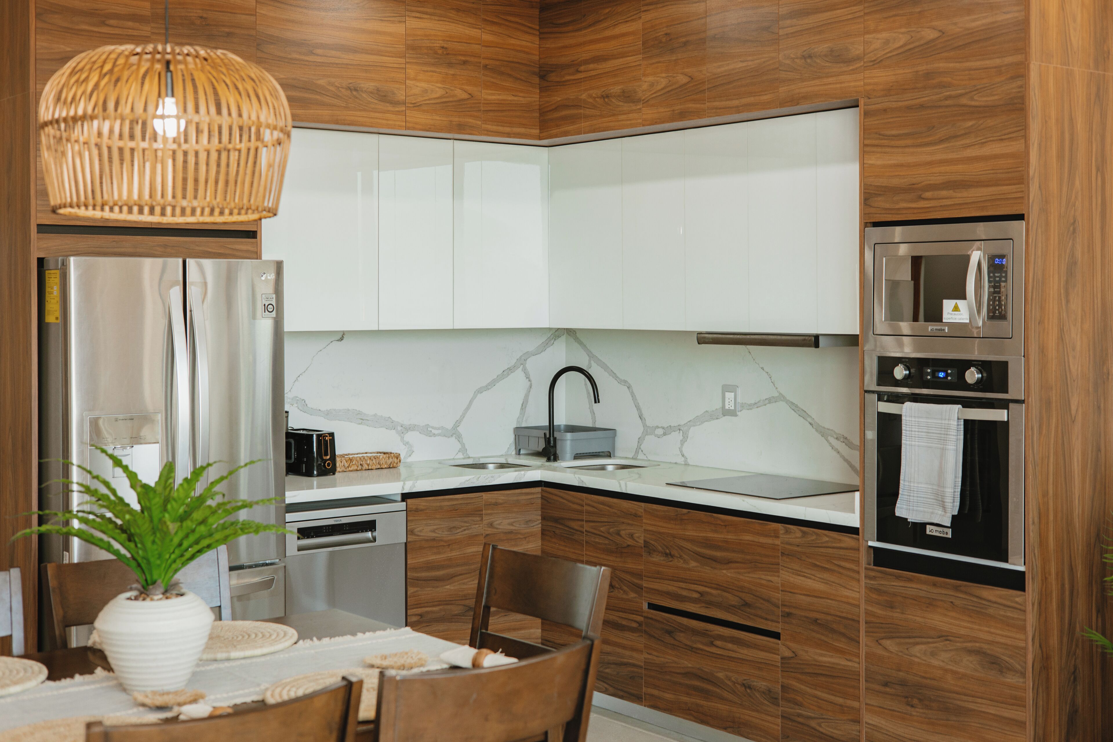 A modern kitchen with wooden cabinets, a stainless steel refrigerator, a microwave, and a built-in oven.
