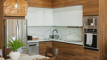 A modern kitchen with wooden cabinets, a stainless steel refrigerator, a microwave, and a built-in oven.