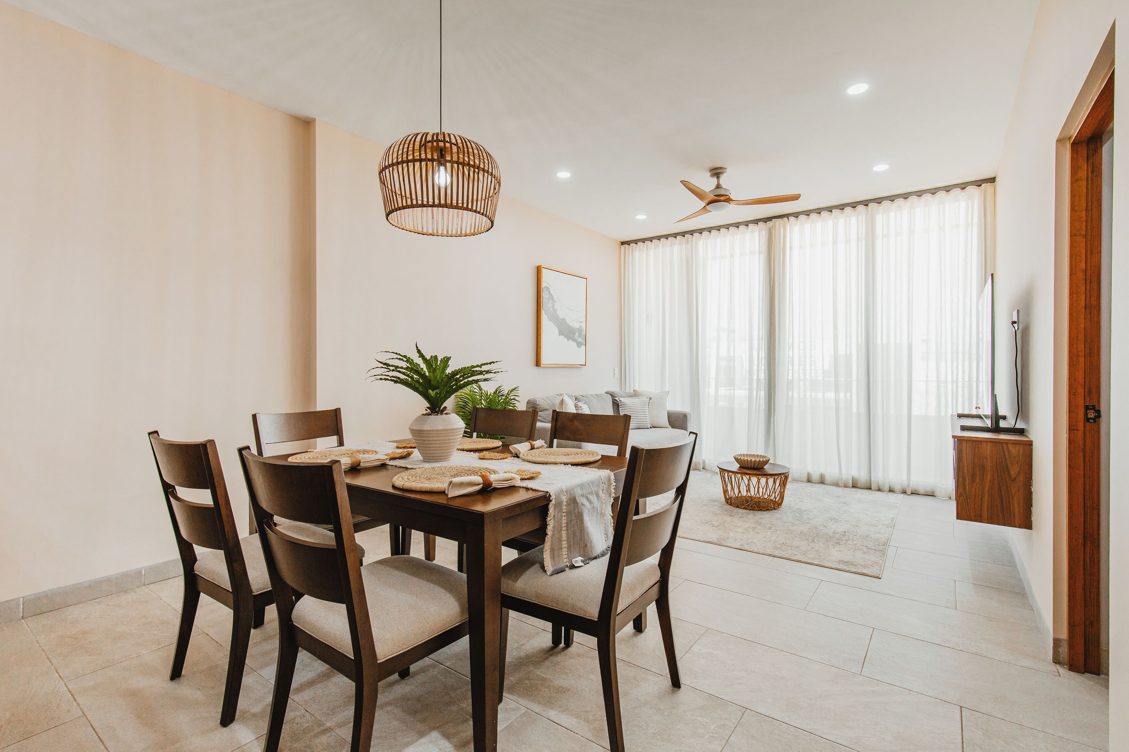A dining area with a wooden table, chairs, and a hanging light fixture.