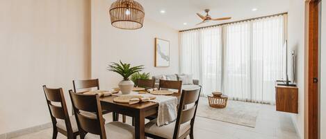 A dining area with a wooden table, chairs, and a hanging light fixture.