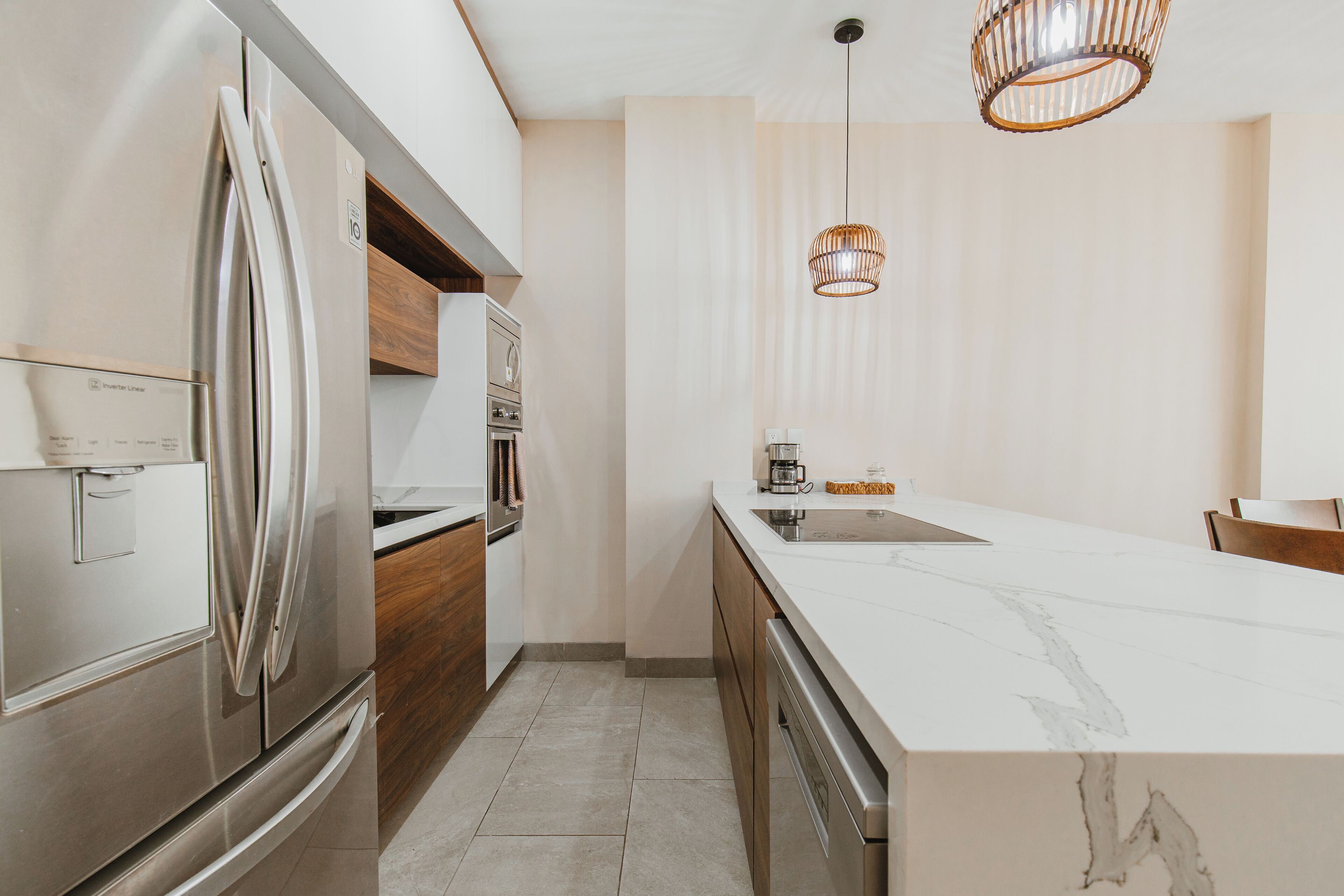 A modern kitchen with stainless steel appliances, a marble countertop, and wooden cabinets.