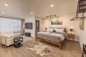 Une chambre moderne avec un grand lit, un canapé, une télévision et un plancher en bois.