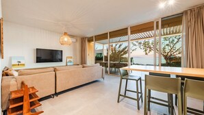 Un salon moderne avec un canapé, un téléviseur et un coin repas.