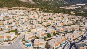 Un quartier résidentiel moderne caractérisé par des immeubles d’appartements aux façades uniformes, des rues bien aménagées et un paysage montagneux en arrière-plan.