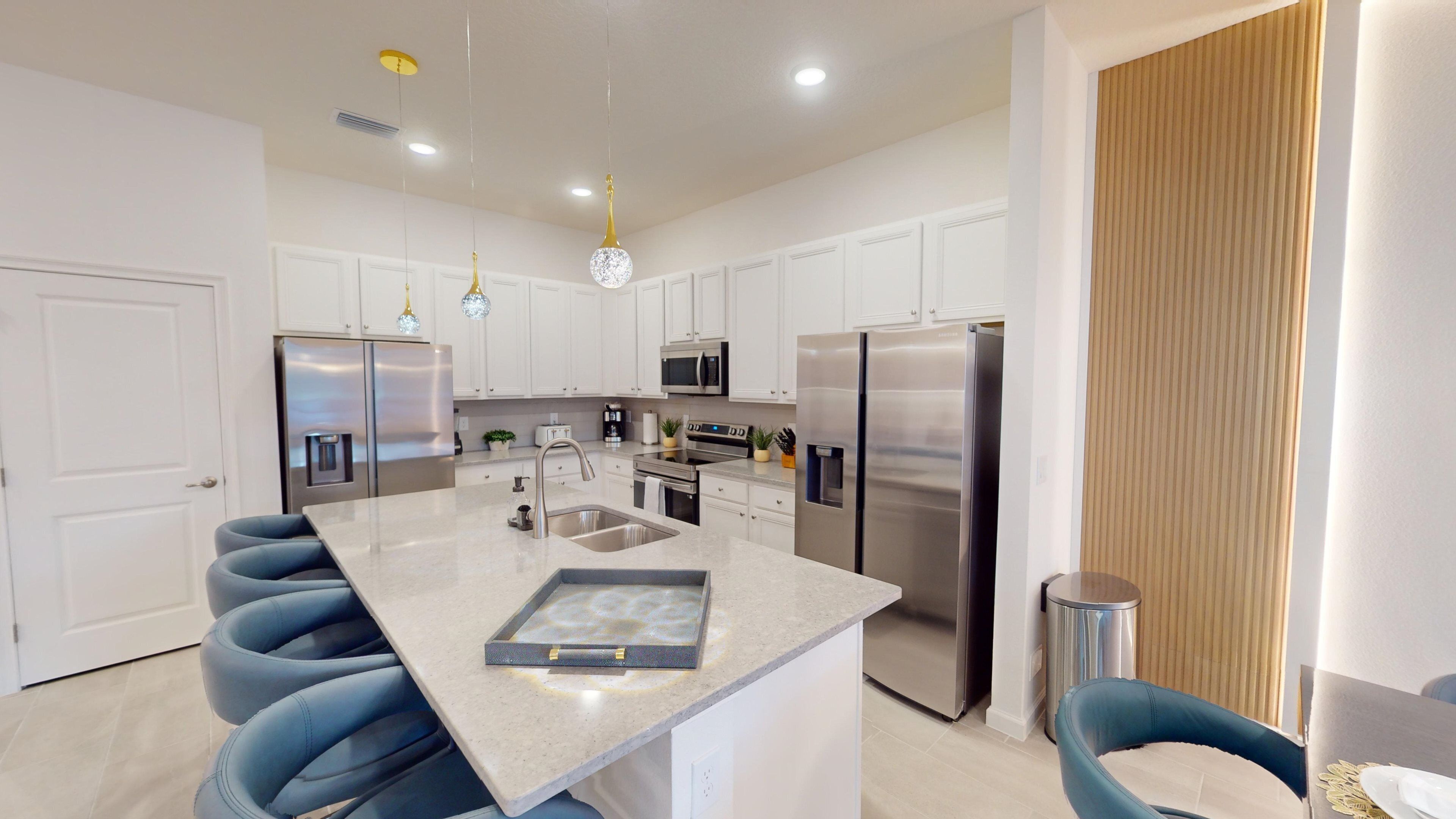 A modern kitchen with white cabinets, stainless steel appliances, and a central island.