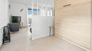 Ein modernes Wohnzimmer mit Fernseher, Sitzgelegenheiten und Blick ins Freie.