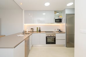 A modern kitchen with white cabinets, stainless steel appliances, and a light-colored countertop.
