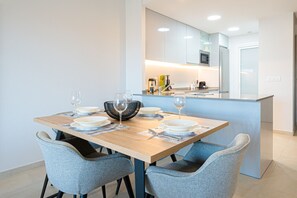 A modern kitchen with a central island, a dining table set with plates and glasses, and light blue chairs.