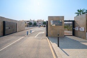 A gated entrance to a residential area with a clear road leading to a building labeled "FAMENGA LAGUE".