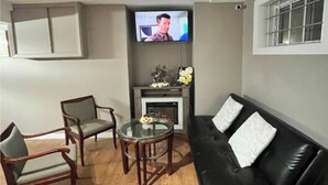 A living room with a black leather sofa, two armchairs, a coffee table, and a flat-screen TV mounted above a fireplace. - #3-Bedroom in a quiet and nice home to stay in West Edmonton Area (Edmonton)