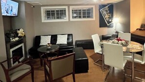 A living room with a black leather sofa, a glass coffee table, a dining table with chairs, a fireplace, and a ceiling fan. - #3-Bedroom in a quiet and nice home to stay in West Edmonton Area (Edmonton)