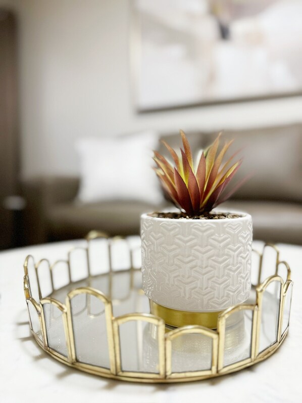 A potted succulent on a white textured pot with a gold wire tray.
