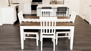Una cucina moderna con mobili bianchi, un tavolo da pranzo in legno e sedie abbinate.