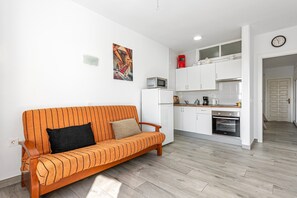 Una cucina moderna con mobili bianchi, un forno a microonde e un tostapane rosso.