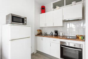 Una cucina moderna con mobili bianchi, un frigorifero in acciaio inossidabile, un forno a microonde, una macchina da caffè e un forno.