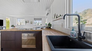 A modern kitchen with a wooden island, built-in oven, and a black sink.
