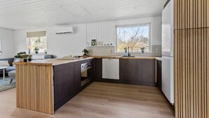 A modern kitchen with wooden cabinetry, a central island, and a large window providing natural light.