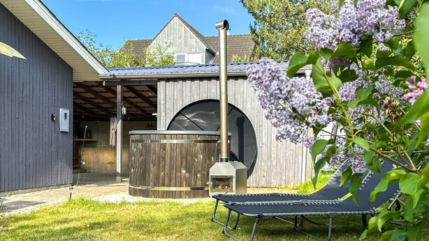 A backyard with a wooden deck, a grill, and a trampoline.