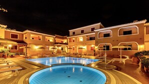Una piscina con borde de baldosas, rodeada por un edificio con varios balcones y zonas de estar al aire libre.
