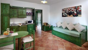 Un espacio habitable compacto con kitchenette, comedor y sofá cama.