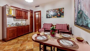 Un comedor con una mesa dispuesta para cuatro, una cocina con armarios de madera y un cuadro en la pared.