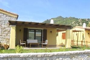 A stone building with a covered patio area, two chairs, and a table.